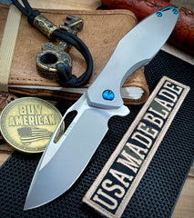 Koenig Arius Patterned Ti Stonewashed M390 Blade with Polished Flats and Blue Ti Hardware AR11211221