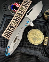 Koenig Arius Patterned Ti Stonewashed M390 Blade with Polished Flats and Blue Ti Hardware AR111211221