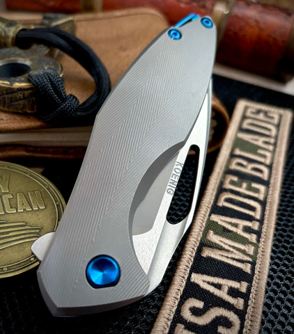 Koenig Arius Patterned Ti Stonewashed M390 Blade with Polished Flats and Blue Ti Hardware AR11211221