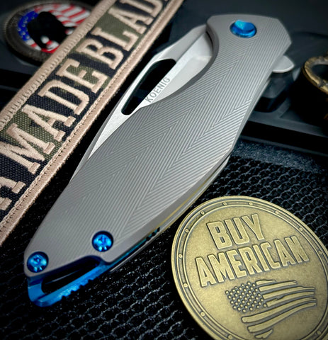 Koenig Arius Patterned Ti Stonewashed M390 Blade with Polished Flats and Blue Ti Hardware AR111211221
