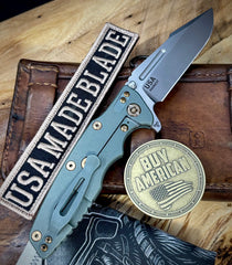 Ammo Can Green Hinderer Eklipse 3.5" Skinny Fullered Harpoon Spearpoint Textured Anodized Working Finish Ti Presentation Side, Smooth Lockside, and Stonewashed Magnacut Blade with bronzed out hardware